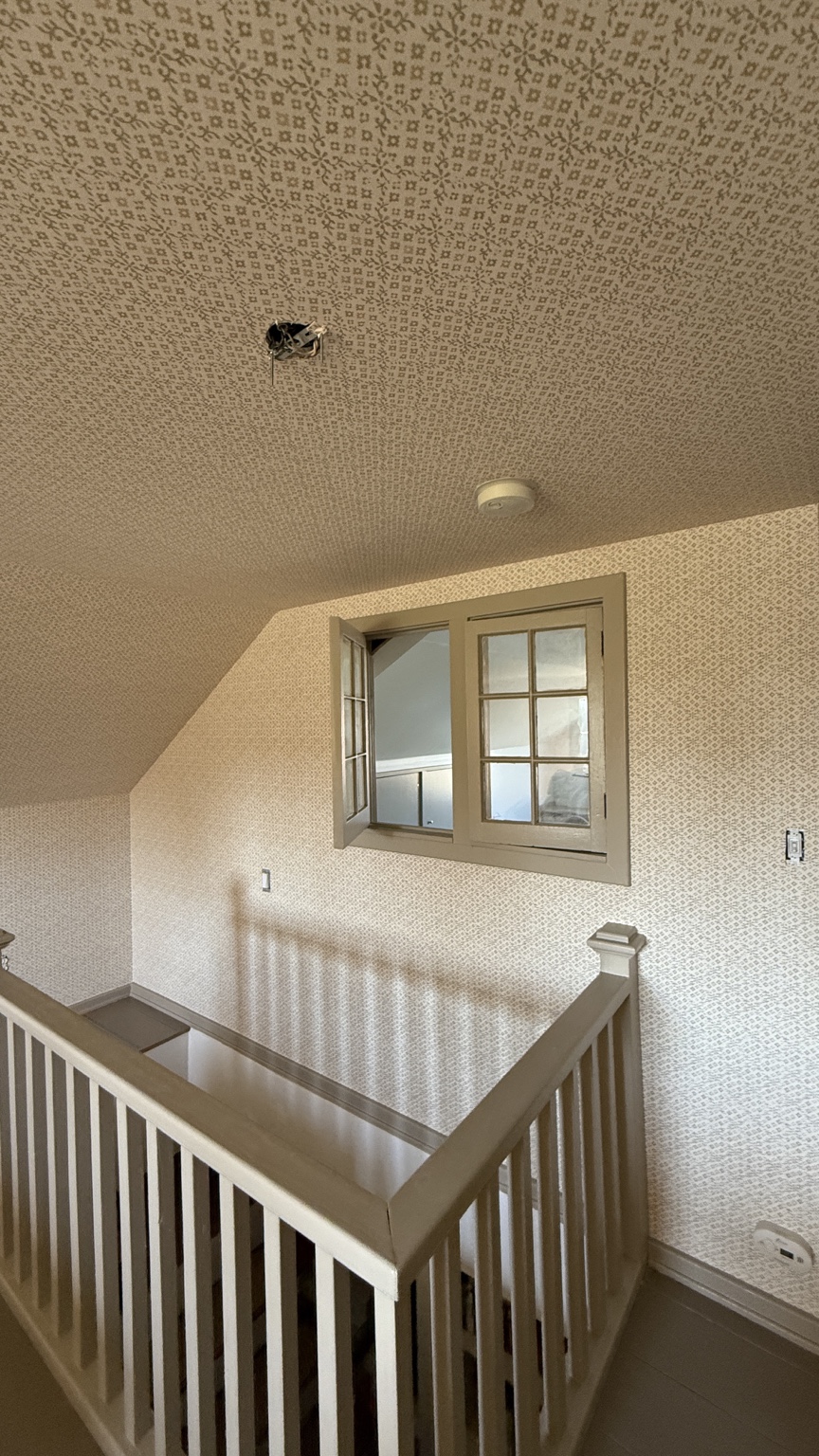 Fine-pattern wallcovering extending across walls and ceiling around a staircase