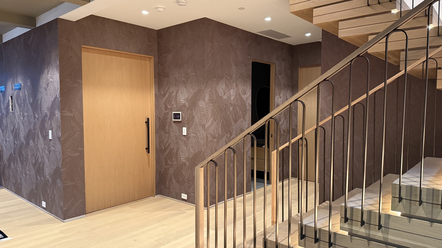 Brown botanical wallcovering installed throughout a contemporary staircase and hallway