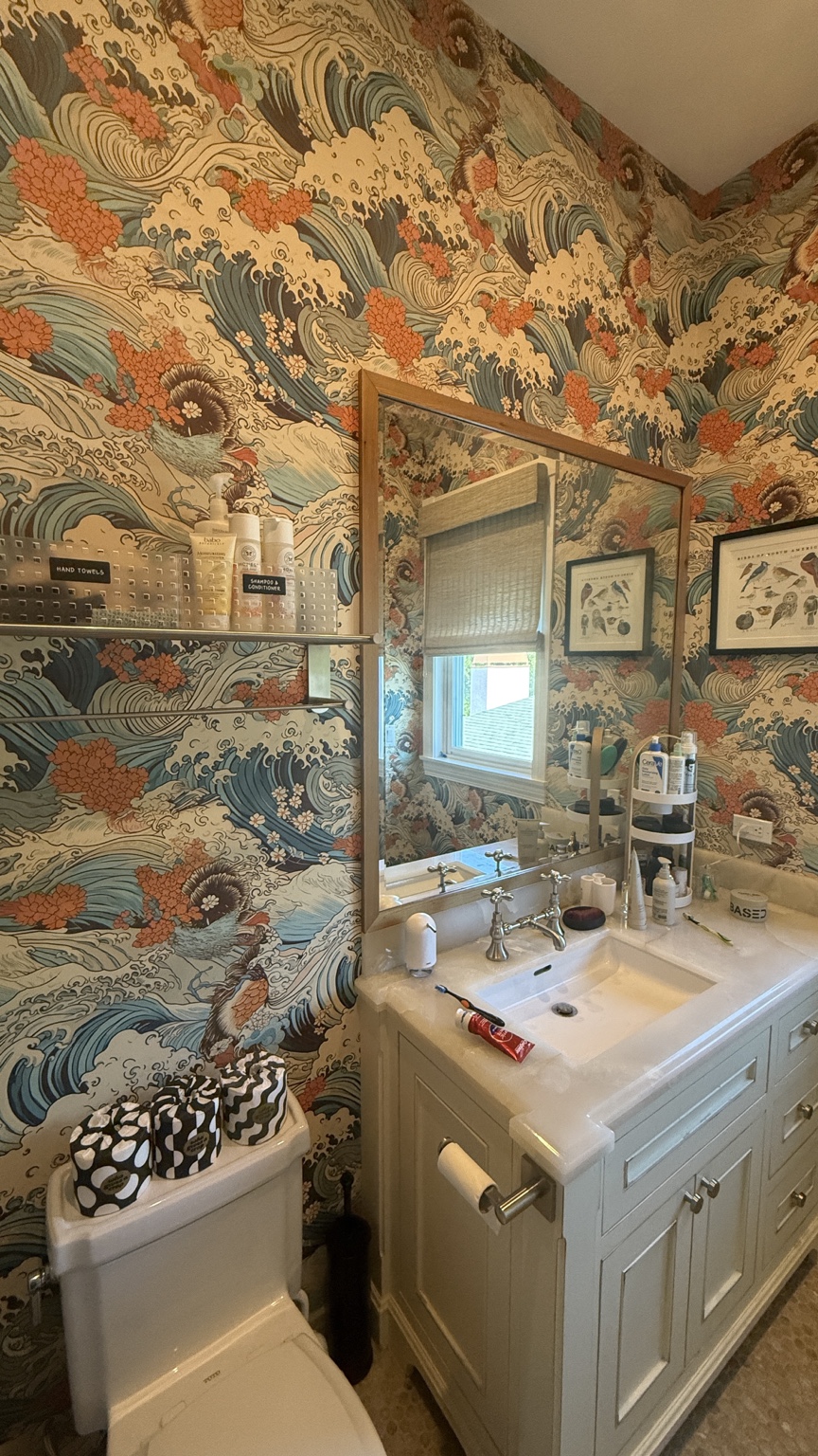 Colorful wave-pattern wallpaper installed around a bathroom mirror and fixtures